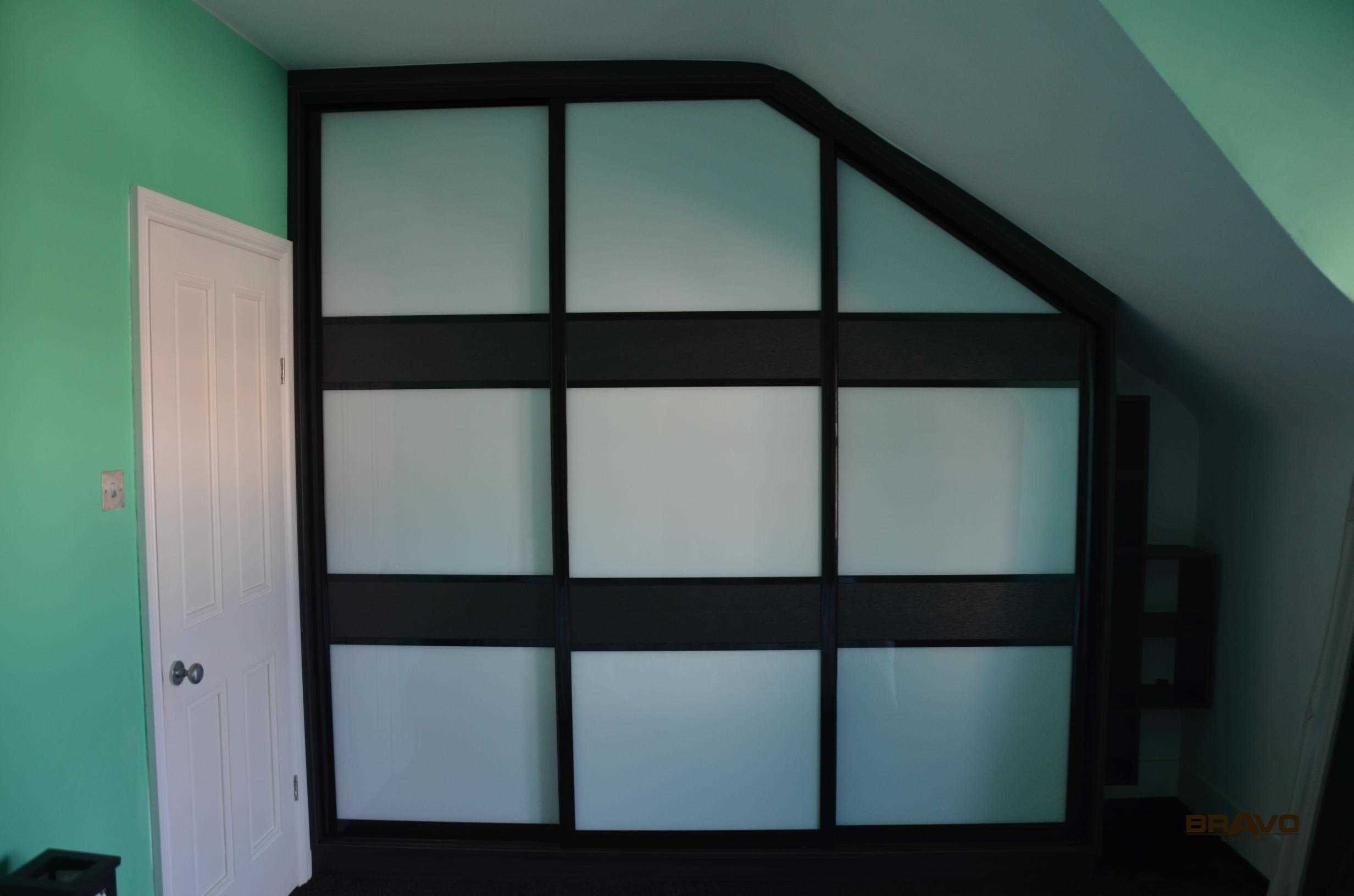 Large black-framed hinged door wardrobes with opaque white panels, set in a room with mint green walls and dark floor trim.