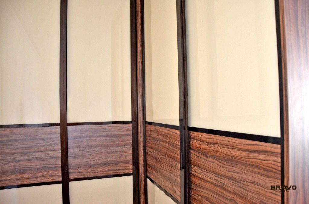 Close-up view of a modern fitted wardrobe with frosted glass doors and metallic handles, showcasing detailed wood grain and craftsmanship.