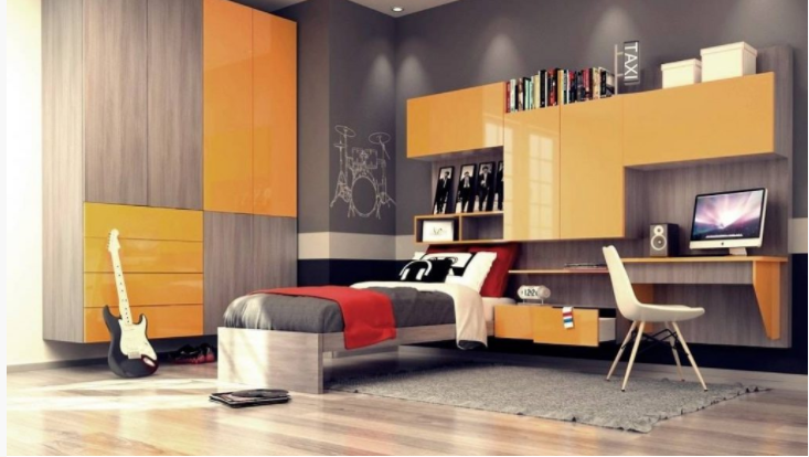 A modern, brightly-lit bedroom featuring a wooden and orange theme, with bespoke furniture including a desk, chair, computer, bookshelf, guitar, and a bed draped in red and grey bedding.