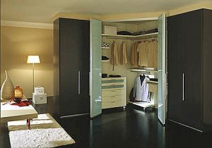 A well-organized walk-in closet with open and closed black hinged door wardrobes displaying various clothes, a white dresser, a red bag on a bench, and soft lighting.