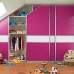 A brightly lit child's room with a large pink and magenta wardrobe featuring hinged doors, toys scattered on the floor, and a cozy corner with a small wooden bench filled with stuffed animals.