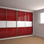A modern room with large red and white checkered hinged door wardrobes, plain white walls, a small white bench, and light brown carpet flooring.