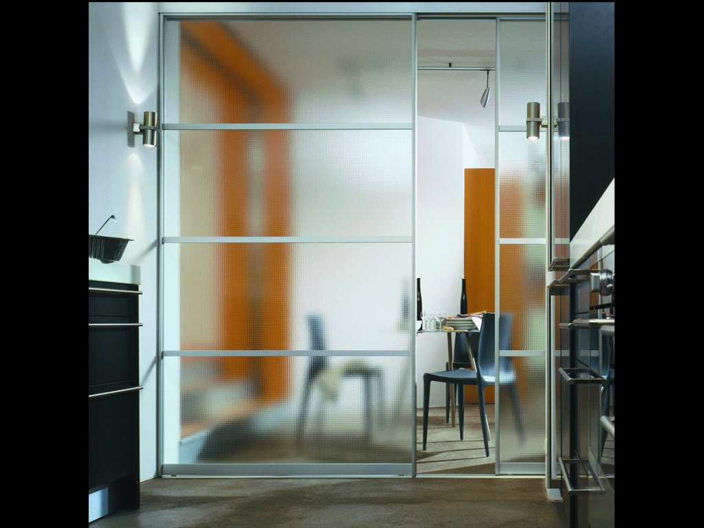 A modern office with frosted glass sliding door wardrobes, providing a glimpse of a blue chair and an orange wall inside, reflecting a sleek and contemporary design.