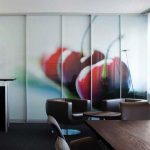A modern office meeting area with bespoke black furniture and a large photographic mural of red cherries on sliding glass panels.