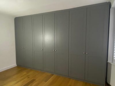grey colour hinged door fitted wardrobe in a bedroom with wood flooring