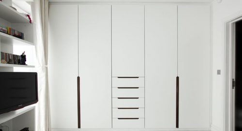 A white colour style inbuilt wardrobe with handles at a low level. 